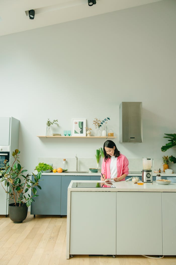 core-values A woman in a pink shirt preparing a smoothie in a modern kitchen environment with natural light.